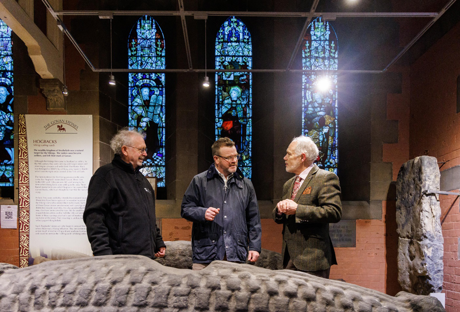 Members of Govan Heritage Trust talk in a room of historic stones